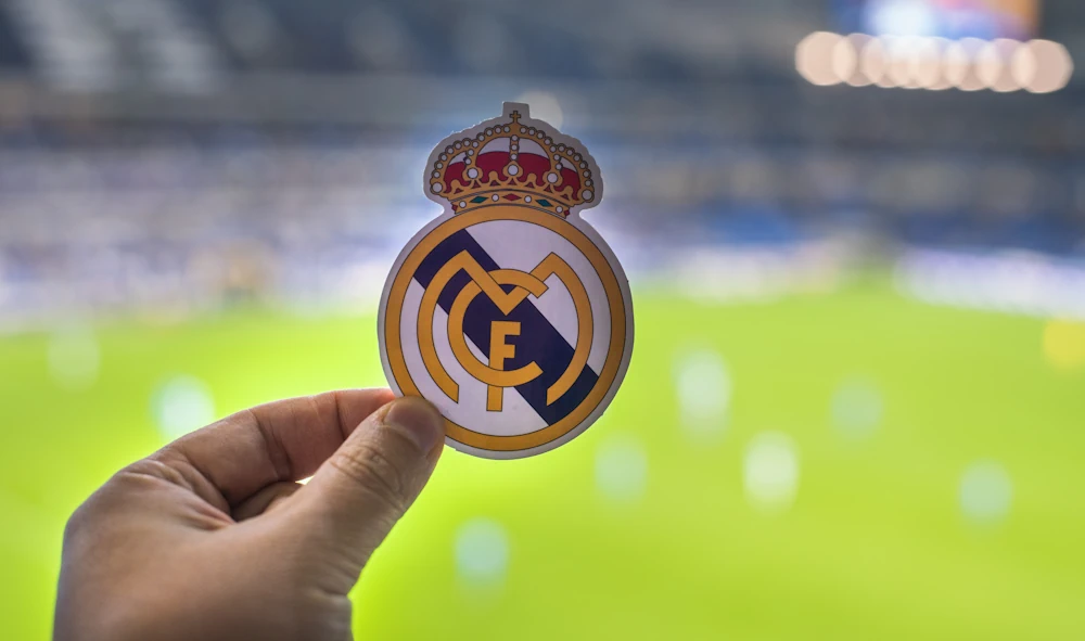 Real Madrid logo with football field in background